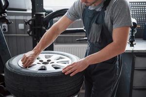 Young man works with wheel's disks at the workshop at daytime photo