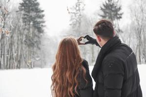 Backing view. Gorgeous young couple have good time together in snowy forest photo