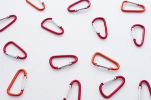 Metal constructions. Many of the red colored carabiners on lying on the white table photo