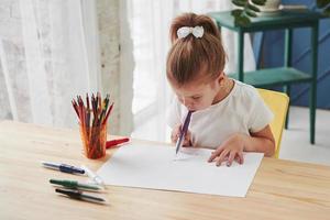 comenzando una nueva imagen. linda niña en la escuela de arte dibuja sus primeras pinturas con lápices y marcadores foto