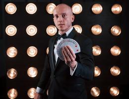 On the work. Magician in black suit standing in the room with special lighting at backstage photo