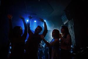 Happy youth. Group of people that enjoying dancing in the nightclub with beautiful lightings photo