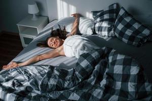 New day has come. Pretty young woman lying on the bed at morning time in her room photo