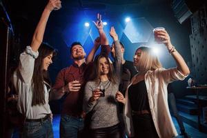 Happy people dancing in the luxury night club together with different drinks in their hands photo