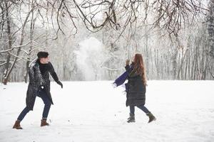 Having fun. Gorgeous young couple playing and throwing snowballs in winter forest photo