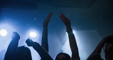 Put your hands up. Group of people that enjoying dancing in the nightclub with beautiful lightings