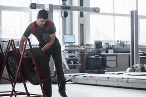 Wheels on the special stand. Mechanic holding a tire at the repair garage. Replacement of winter and summer tires photo