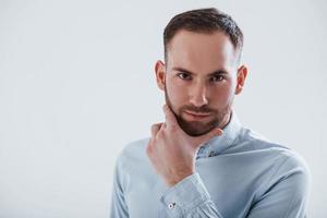 Nice portrait. Man in official clothes stands against white background in the studio photo