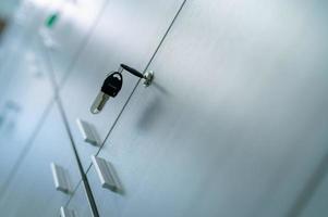 Locker with key in office room. Filing cabinet lock with key for safety and security system in public facility. Secure lock system for document files in business office. White locker door for storage. photo