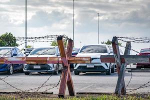 Barbed wire fence of the parking lot. Cars parked at outdoor car parking lot. Car was seized by a lending company. Financial crisis impact on car loan. Used car business. Auto leasing and insurance. photo