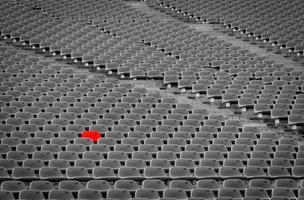 Football stadium with empty seats. Outstanding empty red plastic chair at soccer arena. Row of unoccupied bench at sports stadium. Reserved seating for football game concept. Outdoor audience chairs. photo