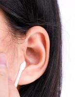 Woman with black hairs is cleaning her ears with white cotton bud. Personal hygiene concept. photo