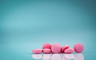 Pink round tablets pills with shadow on gradient background. Pharmaceutical industry. Pharmacy products. Vitamins and supplements. Medication use in hospital or drugstore. Global drug retail market. photo