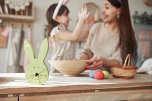 Cute rabbit face toy. Mother and daughter in bunny ears at easter time have some fun in the kitchen at daytime photo