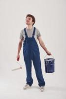 Cheerful look. Man in blue uniform stands against white background in the studio photo