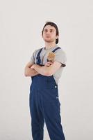 In the hat. Man in blue uniform stands against white background in the studio photo