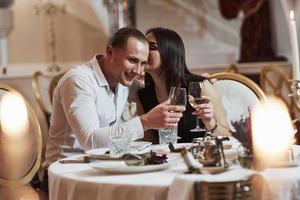 la chica cuenta una historia divertida. una pareja hermosa tiene una cena romántica en un restaurante de lujo por la noche foto