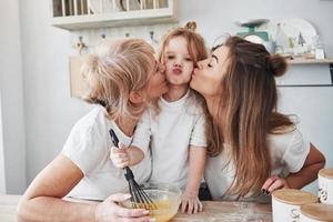 Lovely family. Mother, grandmother and daughter having good time in the kitchen photo