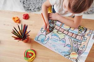 Conception of art. Cute little girl in art school draws her first paintings by pencils and markers photo