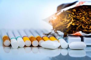 Nicotine chewing gum near pile of cigarettes and tobacco on white background with space. Quit smoking or smoking cessation and lung cancer concept. 31 May  World no tobacco day. photo