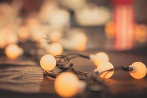 Selective focus decoration lamp light with on black wool and blurred background. Bulb warm light on black and shiny frieze fabric. Christmas day background. bulb light and wire for night party. photo