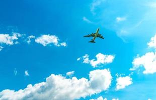 Commercial airline flying on blue sky and white fluffy clouds. Under view of airplane flying. Passenger plane after take off or going to landing flight. Vacation travel abroad. Air transportation. photo