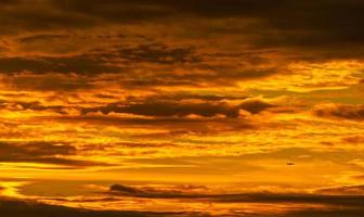 Silhouette small airplane flying on beautiful sunset sky. Golden vast sunset sky. Freedom and calm background. Beauty in nature. Powerful and spiritual scene. Dramatic and majestic golden sky. photo