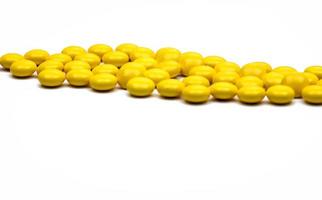 Macro shot detail of yellow round sugar coated tablets pills on white background with copy space for text. photo
