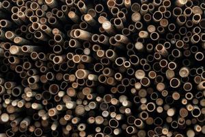 Pile of bamboo pole. Stack of round timber logs. Large batch of wooden logs for industrial scale or manufacturing. Warehouse of material for furniture factory. Art of bamboo abstract background. photo