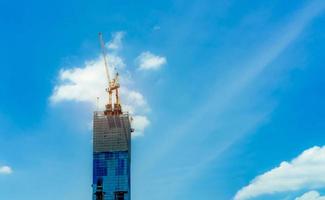 Construction site with crane and building. Real estate industry. Crane use reel lift up equipment in construction site. Building made of steel and concrete. Crane work against blue sky with sunlight. photo