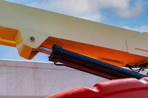 Closeup hydraulic of boom lift. Orange articulated boom lift. Maintenance and repair hydraulic boom lift service. Aerial platform. Telescopic boom lift. Mobile construction crane. Hydraulic cylinder. photo