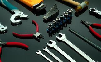 Set of mechanic tools on dark background. Chrome wrenches or spanners, hexagon socket, end cutter pliers, locking pliers, pincers, feeler gauge, bent wrench and hammer. Chrome vanadium spanner wrench. photo