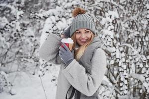 Happy young woman. Portrait of cute blonde in warm clothes that enjoying spending her weekend outdoors in the winter forest photo