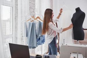 ajusta el tamaño. diseñadora de moda femenina trabaja en la ropa nueva en el taller foto