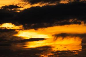 cielo dorado del atardecer con nubes oscuras. belleza en la naturaleza. fondo abstracto hermoso del cielo de la puesta del sol. cielo naranja y amarillo con nubes negras al atardecer. cielo al anochecer. concepto pacífico y tranquilo. foto