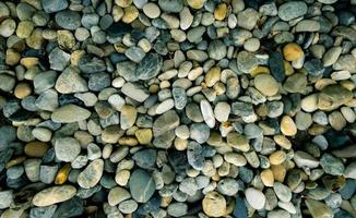 fondo de textura de piedra pequeña. piedra de guijarros en la playa. Piedra de río para decoración de jardines. roca gris de textura suave con patrón natural. vista superior del suelo de roca. grava de guijarros material de construcción. foto