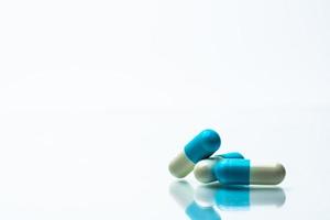 tres pastillas de cápsulas azules y blancas sobre fondo blanco con sombras y espacio para copiar texto. foto