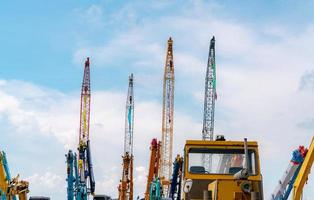 Crane against blue sky and white clouds. Real estate industry. Red and yellow crawler cranes use reel lift-up equipment. Crane for rent at the parking area. Crane dealership for construction business. photo