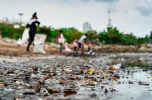 Blurred of volunteers collecting garbage. Beach environment pollution. Volunteers cleaning the beach. Tidying up rubbish on beach. Oil stains on the beach. Oil leak to the sea. photo