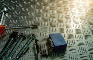 Top view of tools on industrial metal checker plate. Metal checkerplate for anti skid. Nut, bolts, and hex key on metal sheet floor. Silver bump ground with art pattern. Silver texture background. photo