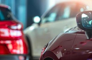 Closeup side mirror of red car on blurred SUV parked in modern showroom. Car dealership. Auto leasing concept. Car stock in showroom. Car sale decline impacted from coronavirus crisis concept. photo