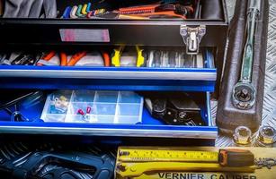 Closeup of tools in box on checkered plate background in workshop. Service tools set. Home building and electrical tools. Plumber hand tools. Technician equipment for repair work. photo