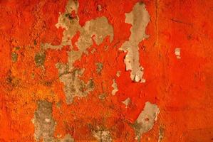 Orange color painted on concrete wall are peeling. Old and dirty wall texture background with space. photo