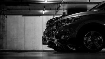 Car parking in shopping mall underground parking lot. Indoor car parking. Black and white scene of car parked at basement of building. Side view of SUV car parked in row at night. Automotive industry. photo