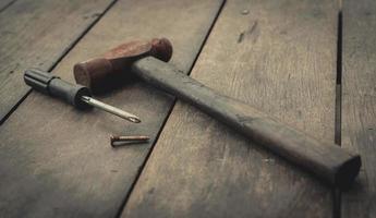 Old rusted hammer, screwdriver and nail on old wooden table. Woodwork tools for fix and repair home. Carpentry tools on an old workbench. DIY tool kit. Equipment for construction in house. Home fix. photo