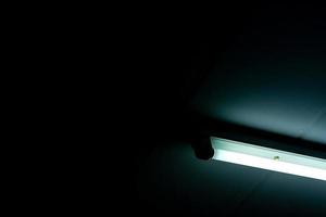 Opened LED light tube on dark background. LED fluorescent lamp light. Lighting equipment. Lamp light interior. Energy saving light bulbs installed on the ceiling in room of house concrete building. photo