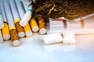 Nicotine chewing gum near pile of cigarettes and tobacco on white background with space. Quit smoking or smoking cessation and lung cancer concept. 31 May World no tobacco day.