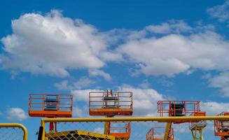 Articulated boom lift. Aerial platform lift. Telescopic boom lift against blue sky. Mobile construction crane for rent and sale. Maintenance and repair hydraulic boom lift service. Crane dealership. photo