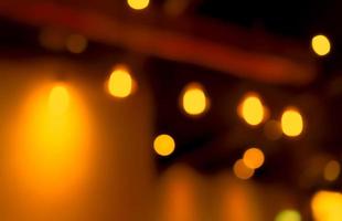 Blurred orange and yellow bokeh abstract background. Blur bokeh on dark background of restaurant in the night. Light effect with beautiful pattern. Decorative golden lights bulb bokeh. photo