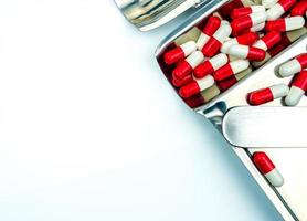 Top view of red-white antibiotic capsule pills on stainless steel drug tray. Antibiotc drug resistance. Prescription drugs. Pharmaceutical industry. photo